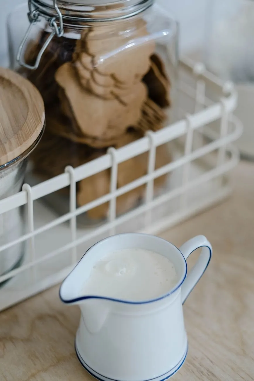 Small white enamel jug with a blue rim holding milk on a kitchen worktop